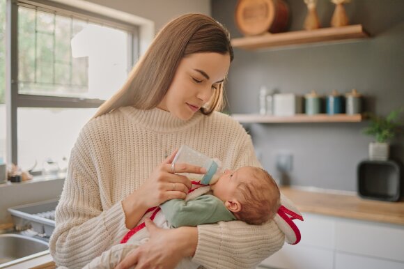 Newborn, baby and mother milk bottle drink of a young mama in a home kitchen with love and care. Calm happiness of a mom holding her child in a family house while her kid is drinking formula